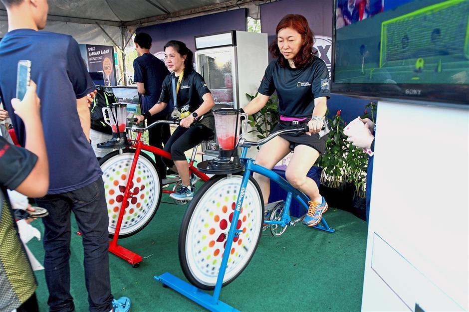 Runners having fun cycling to power up blenders attached to their stationary bikes for a cup of refreshing watermelon juice.