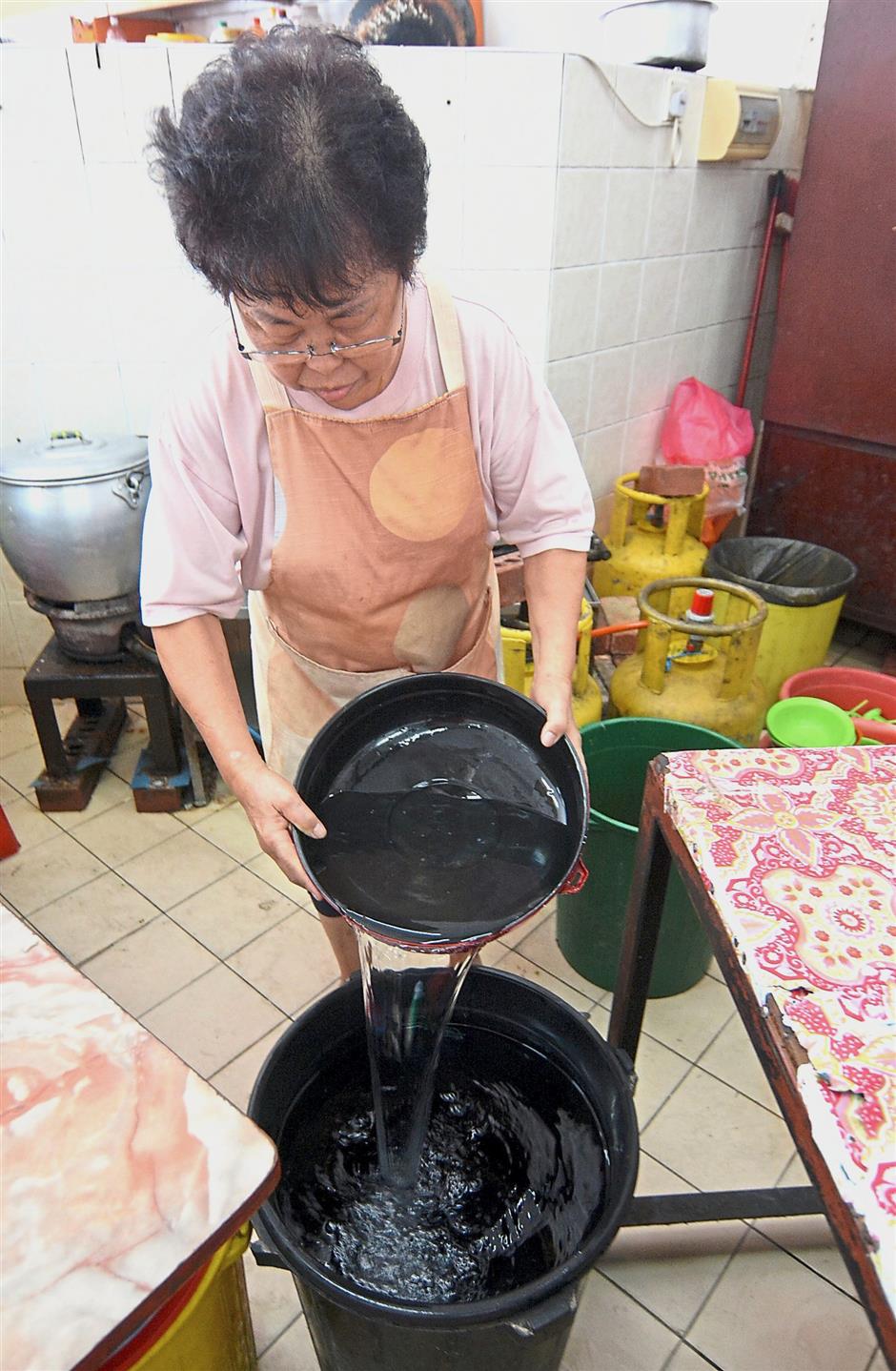 Stall owner Chan Chew Tai, 63, transferring water into a pail to  prepare for the water disruption