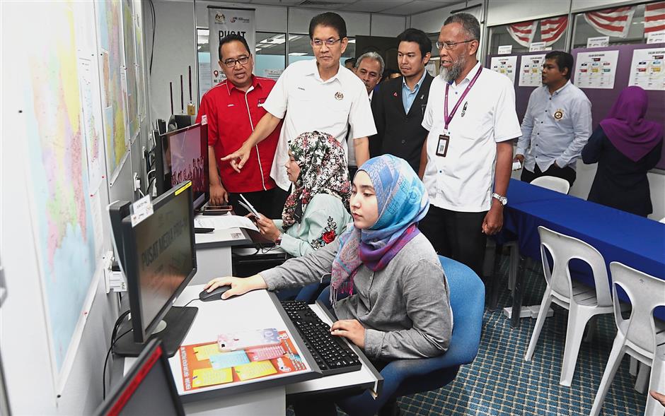Zainal Abidin (second left) with Fuad (right) observing reporters at work at the media centre in Bangunan Mara, Weld Quay. (Right pic) The Campbell Street arch in George Town is decorated with Pakatan common flags.