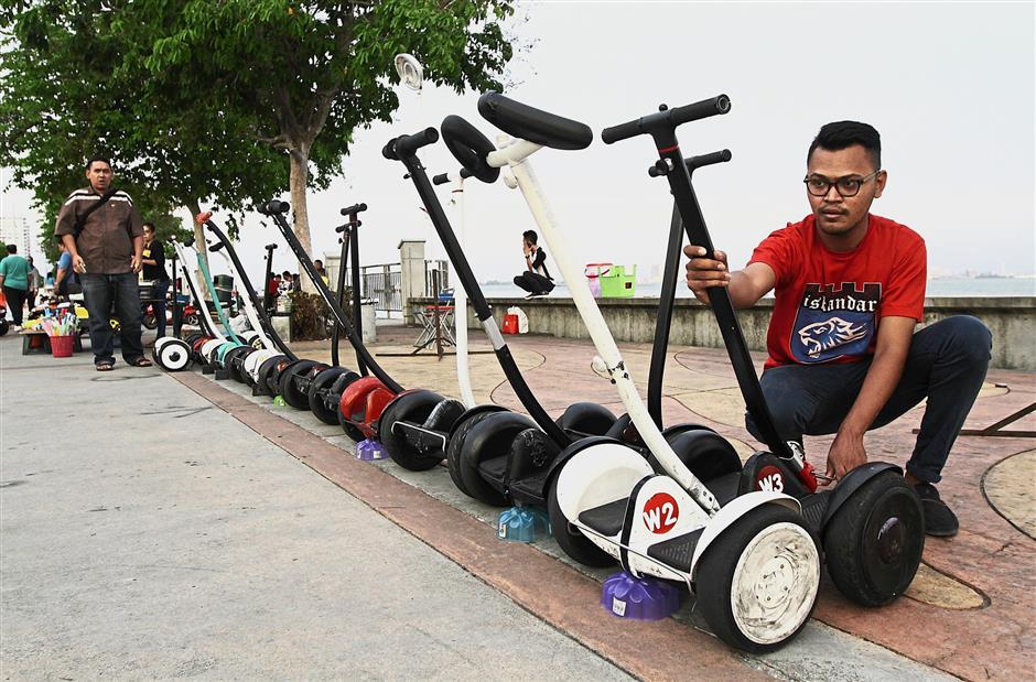 Mohd Nasrudin arranging the Ninebot scooters that he rents out for recreational purpose after obtaining a permit.