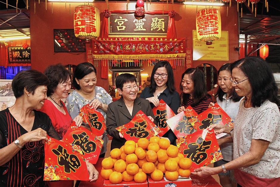 Ooi (centre) and her members showing the ‘fu’ character after presenting a cheque to the temple committee.