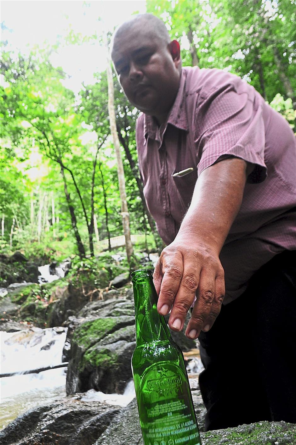 Zuhairy Abdul Karim from Pertubuhan Gagasan Prihatin Semenyih removing a bottle from Sungai Tekala Recreational Forest. The  community  welcomes visitors but not the trash they leave behind.