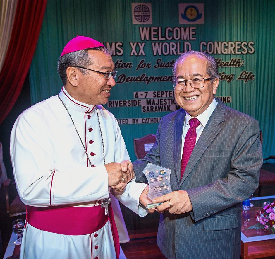 Archbishop of Kuching Simon Poh (left) presenting a souvenir to Uggah at the congress in Kuching.