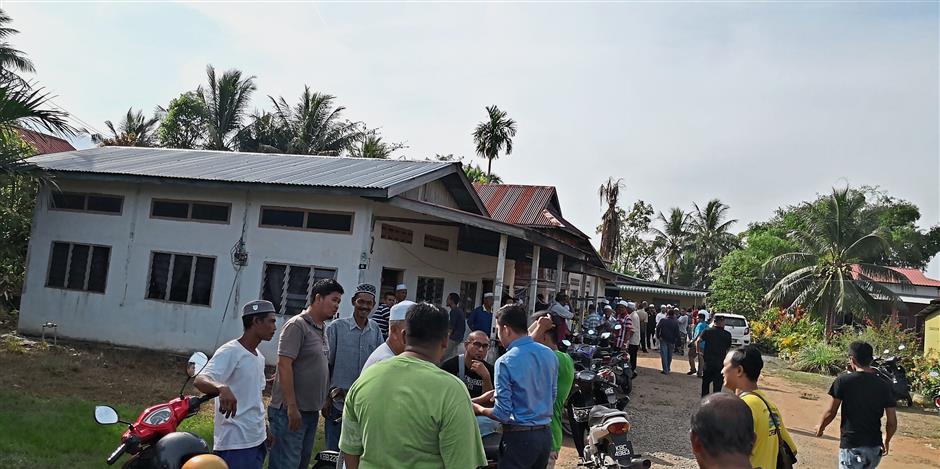 Scene of the crime: Villagers gathering outside the house where the attack took place in Yan.