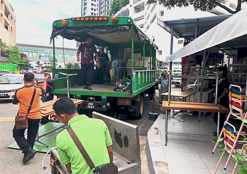 DBKL officers dismantling a stall with extensions on a public walkway along Jalan Sepadu.