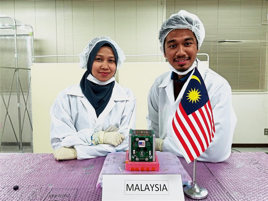 (From left) Syazana Basyirah and Muhammad Hasif pose with the UiTMSAT-1.