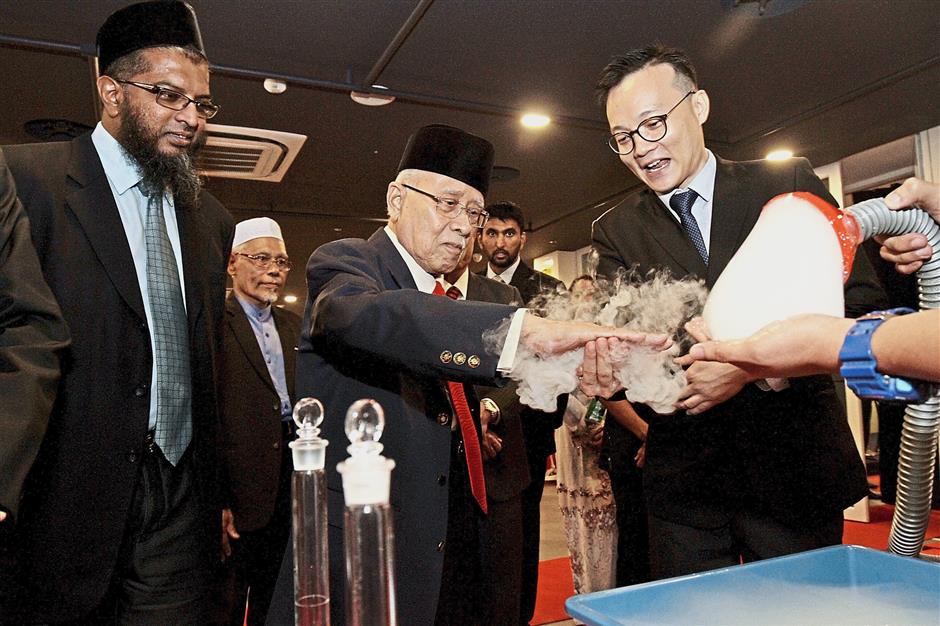Abdul Rahman (middle) checking out an experiment, watched by National Institute of Biotechnology Malaysia research director associate professor Dr Md Azman Seeni Mohamed (left) and Tech Dome education and exhibits manager Sean Lee.