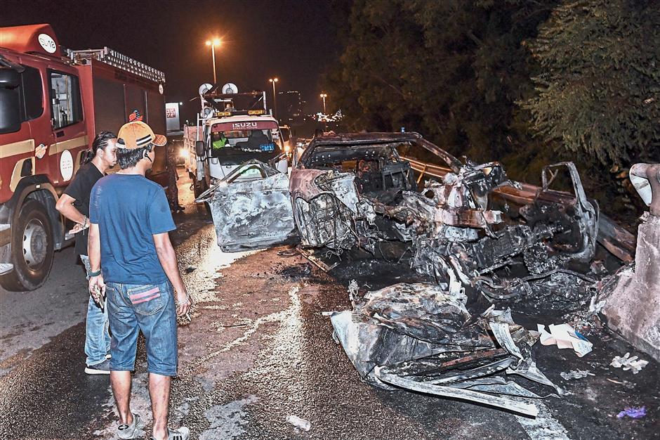 Grim scene: Onlookers surveying the wreckage after the tragic incident which happened at KM6.9 along the Silk Highway heading towards Sungai Long, Kajang. — Bernama