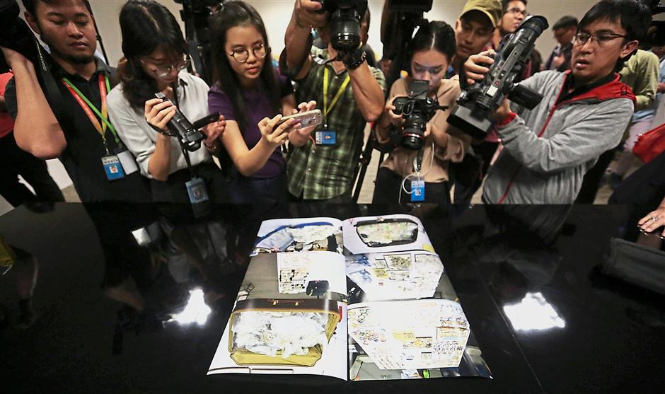Visual proof: Journalists taking photos of images of items seized in the 1MDB probe during a press conference at the CCID headquarters in Kuala Lumpur. (Inset) Comm Amar briefing the press on the items seized. — The Star / Reuters