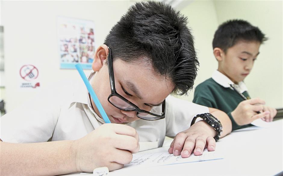 Caiyen (left) and Caysen work on their Kumon worksheets at the centre.