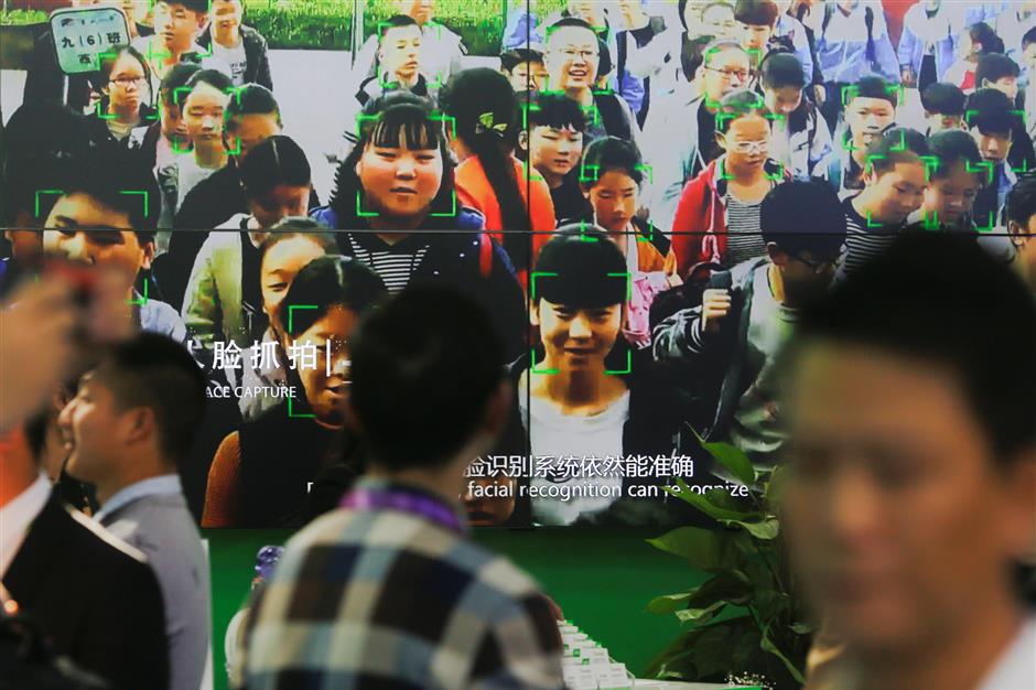 Visitors walk past a screen showing a demonstration of facial recognition software at the Security China 2018 exhibition on public safety and security in Beijing, China October 23, 2018.  Picture taken October 23, 2018.   REUTERS/Thomas Peter