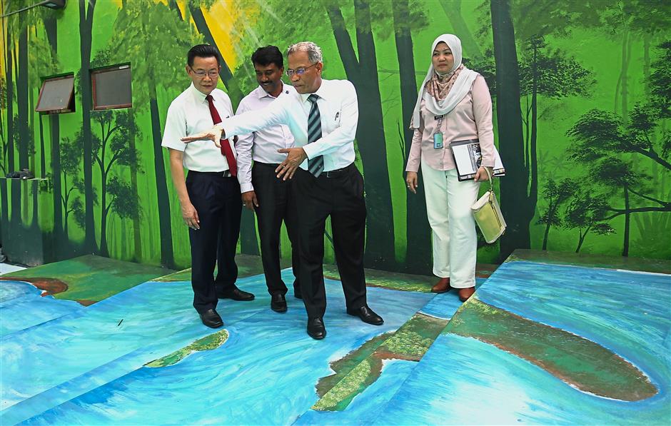 Mahadi (second from right) explaining to stakeholders the concept of the Alor stream at the project site. Looking on is Natasha (right).