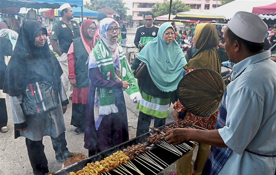 PAS candidate for Kepala Batas Siti Mastura Muhammad (green scarf) talking to market traders during her walkabout in Pinang Tunggal.
