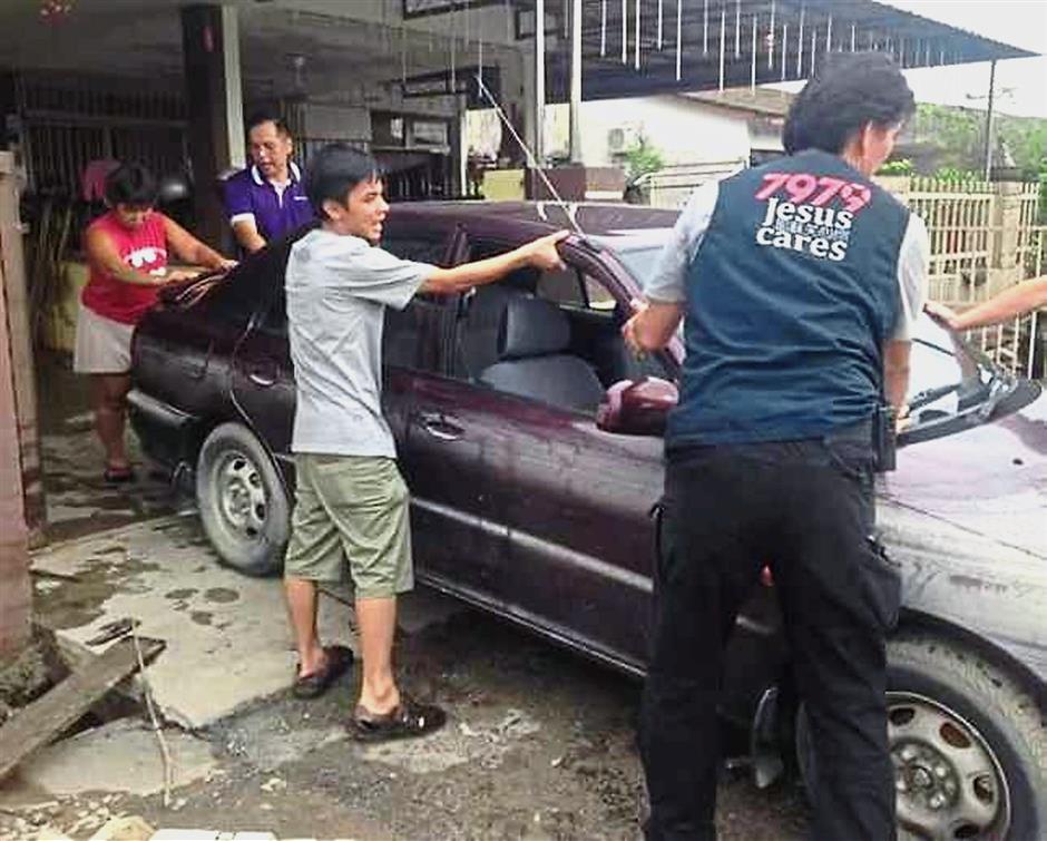 Car trouble: Flood victims moving a car which was inundated by the floodwaters last week.