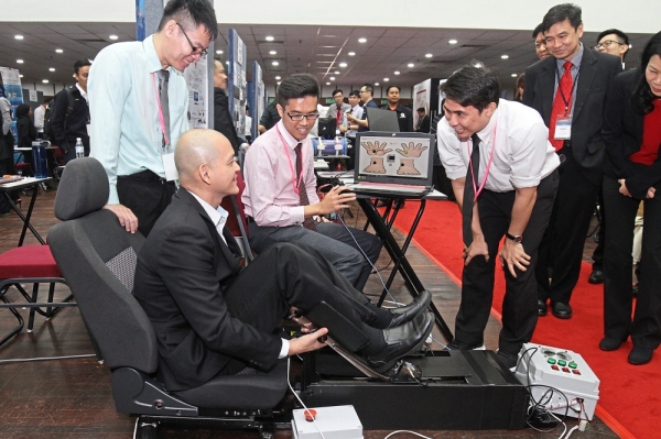 Ong trying out the stroke rehabilitation machine as the winning team members explain how the machine works.