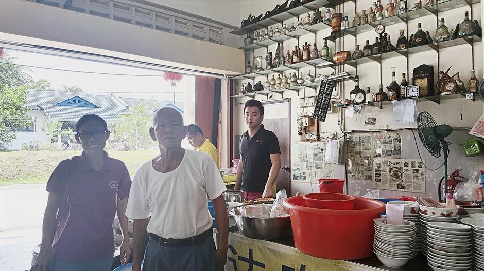 Chin (left) with three generations in the Loh family, Chin Seng (second from left), Pak Choy (yellow shirt) and Jing Xian (black shirt) at their shop in Kampung Baru Paya.