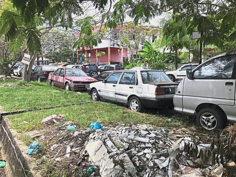A row of abandoned cars along the pavement of Jalan Damar in Permatang Damar Laut.