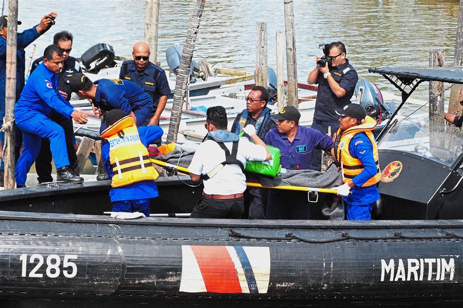 To safety: Rescuers carrying the 47-year-old Chinese national who was saved after being trapped in the sunken vessel’s engine room.