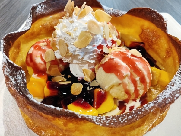 Dutch Baby, a pancake bowl baked in a hot cast iron, filled with ice cream and lashings of preserved fruit jam.