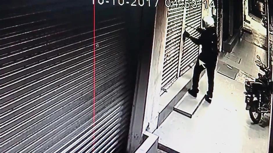 A CCTV recording showing the thief inserting an object to prise open the shutter lock.