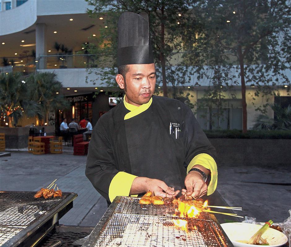 Khairul grilling satay at the live cooking station.