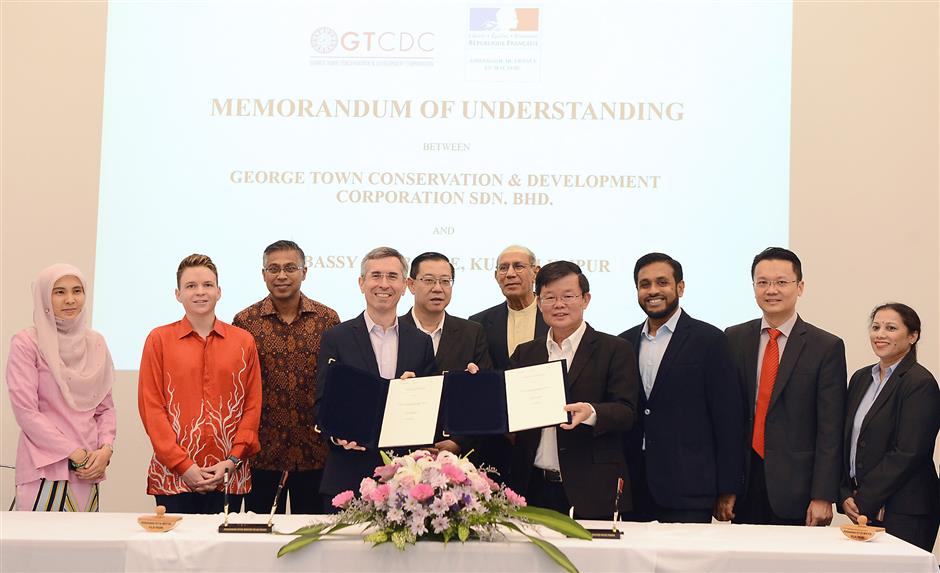 Laplanche (fourth left) exchanging MoU documents with Chow (fourth right) at Bangunan UAB in China Street Ghaut, George Town. With them is Lim (next to Laplanche).