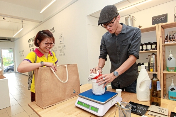 Nude owner Wilson Chin weighing an item for a customer, Alice Lim.