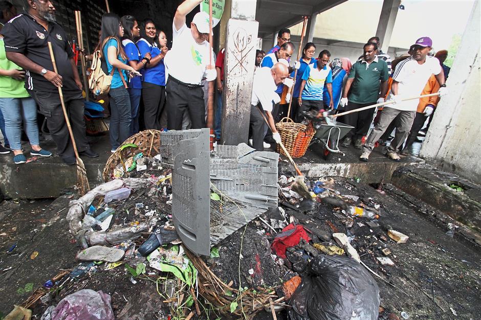 Zambry (right, wearing cap) helped to clear the rubbish during the gotong-royong in First Garden Flats. — Photos: RONNIE CHIN/The Star