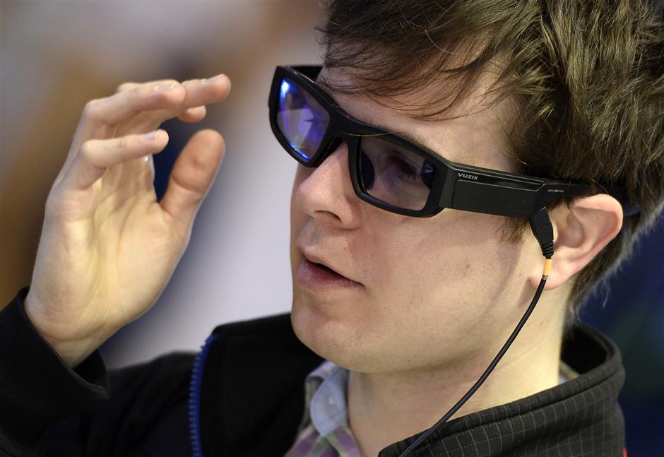 A young man tries new Vuzix Blade augmented reality smart glasses Prosumer on the first day of the Mobile World Congress (MWC) on February 26, 2018 in Barcelona. The Mobile World Congress, the world's biggest mobile fair, is held in Barcelona from February 26 to March 1.  / AFP PHOTO / Josep LAGO