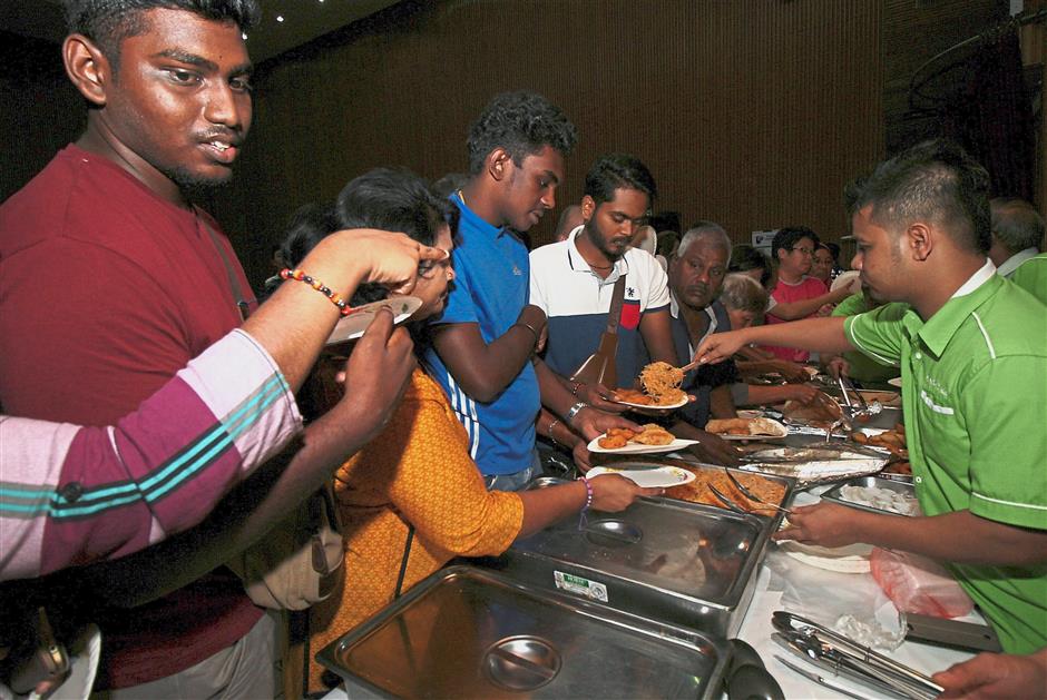 (Left) NGO representatives lighting the ‘Kuttu Vilakku’ (Indian oil lamp) at the opening. (Right) Guests tucking into the sumptuous spread of buffet food served.