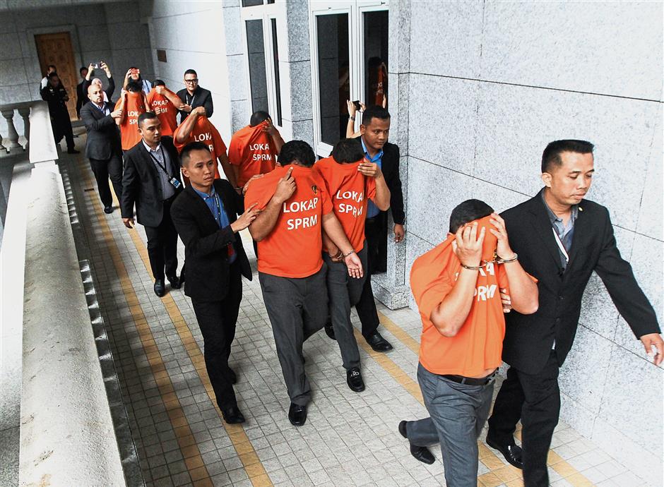 Taken away: MACC officers escorting the seven PMD officers at the magistrate’s court in Putrajaya. Inset: Hasanah
