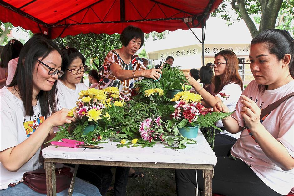 Saying it with flowers: Volunteers and students arranging the flowers for the float.