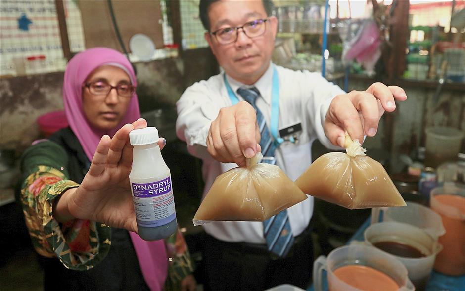 Ong (right) and Northeast district health officer Dr Umarazina Abdul Kadir showing the ketum and cough syrup found at a beverage stall during the raid.