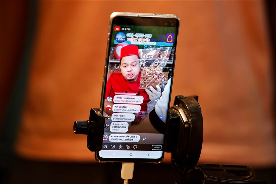 Anurak Sareuthai is seen on a mobile phone as he sells dried seafood products during a Facebook live event at his house in Satun province, southern of Thailand, May 30, 2019. Picture taken May 30, 2019.  REUTERS/Jiraporn Kuhakan NO RESALES. NO ARCHIVES.