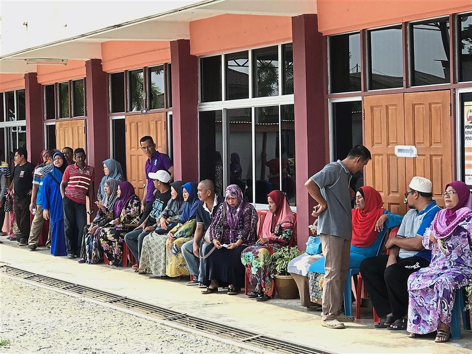 Elderly voters taking a seat while waiting in queue to vote at SK Sungai Burong in Tanjong Karang.
