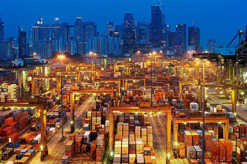Building link: The skyline of Singapore’s central business district is seen at dusk as operations continue at a PSA International port terminal in Singapore. K2 envisions building a bridge between Singapore and the Silicon Valley. — Reuters