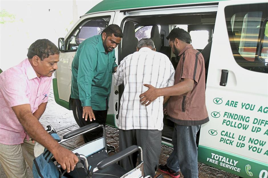 Social service: Sashitharaan (in green shirt) and Chandrasegaran (in brown shirt) assisting a patient into the van following a dialysis session at a private medical centre in Klang.