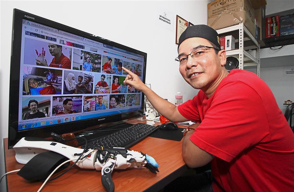 Sujana showing pictures of recipients of the prosthetic arms he has made. — SAIFUL BAHRI/The Star
