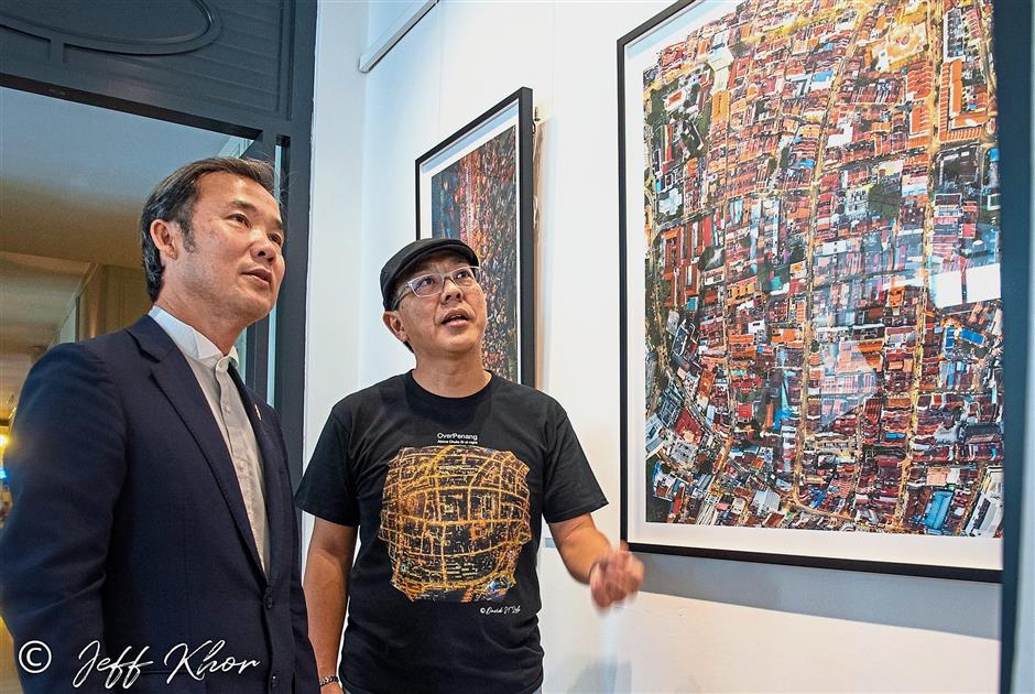 Loh (right) briefing Yew on one of the exhibits of his ‘Over Penang’ showcase at the E&O Hotel.