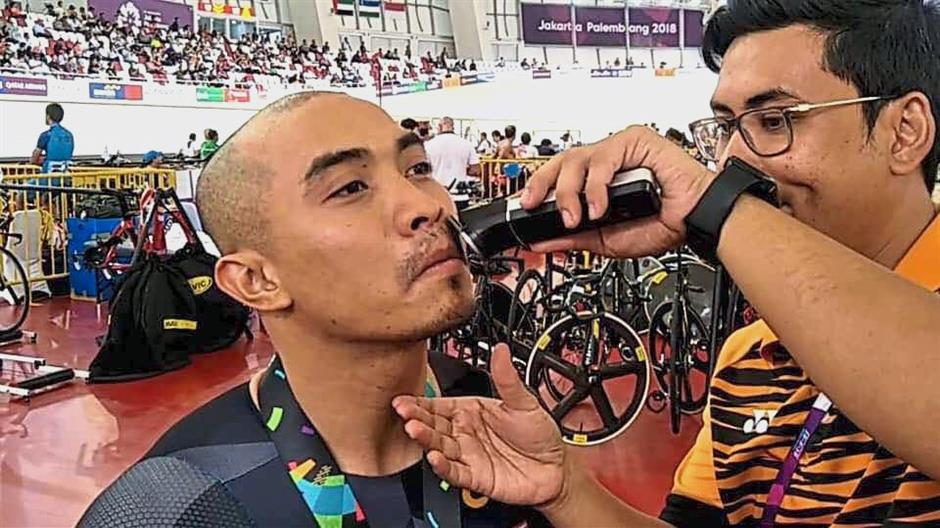 National track cyclist Azizulhasni Awang getting his mustache shaved by an Malaysian official.