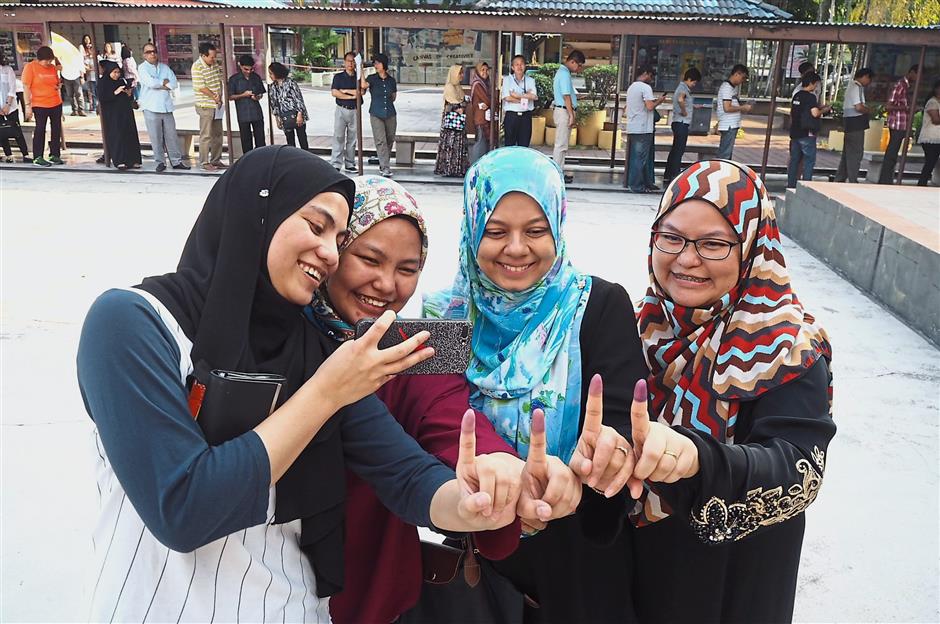 Zunaira (left) cast her vote with her sisters Nurul Farina (second from left) and Noor Hidayah Zakaria (right), and their neighbour Raihan Rahmat (third from left).