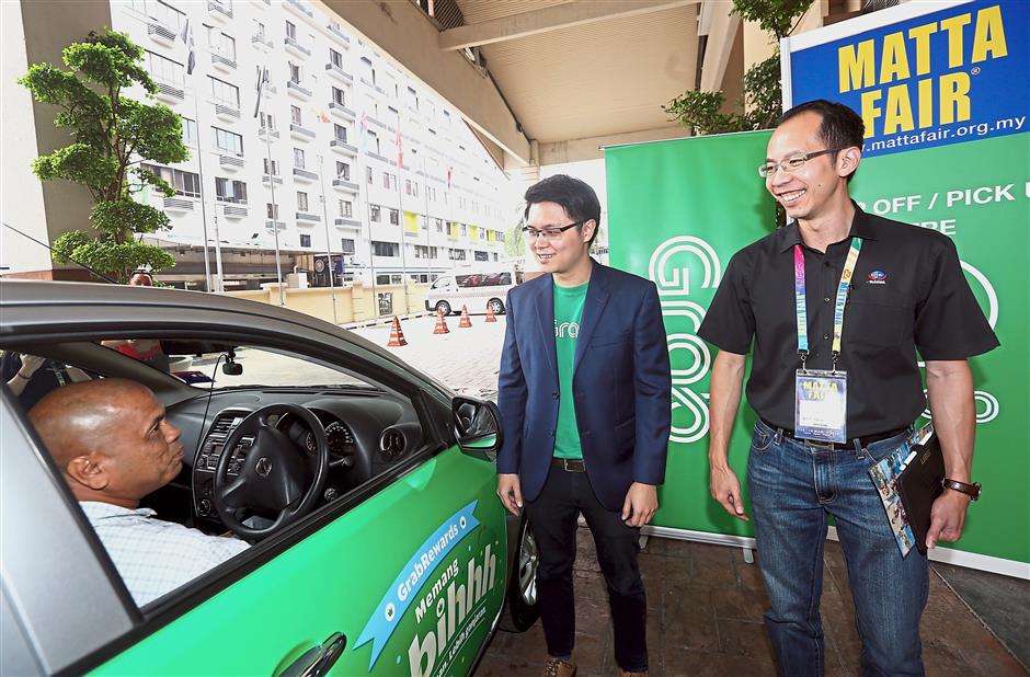 Grab business development head JJ Tan (centre) and MATTA honorary secretary-general Nigel Wong launching the Grab service at the fair.