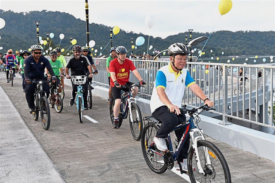 Chow (front) with Lim (in red T-shirt) and other officials enjoying a ride on Jambatan Harapan during the launch.