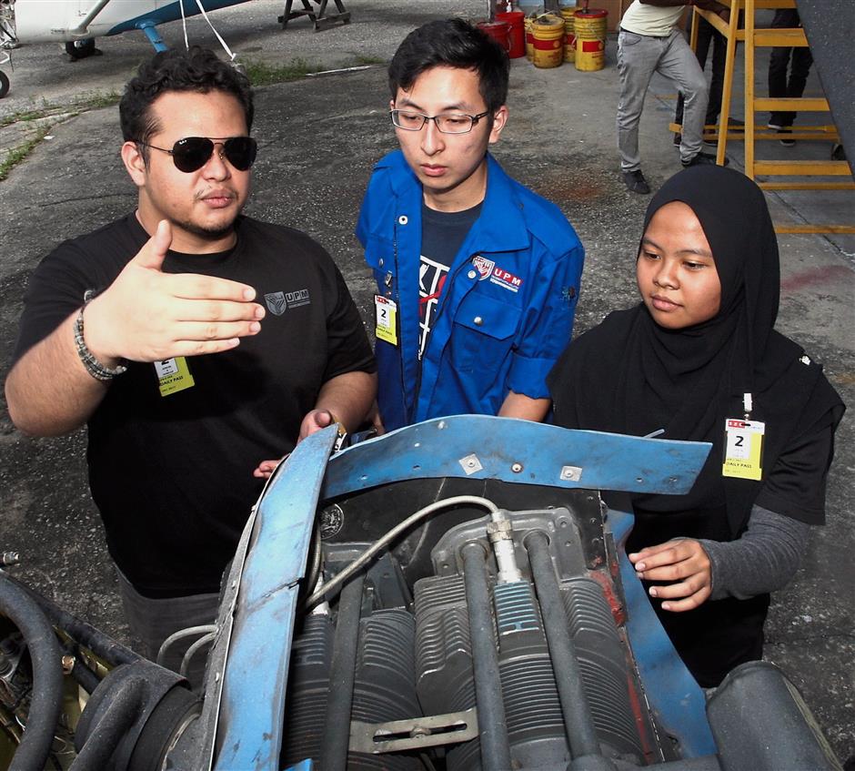 (From left) Muhammad Fakhrul, Tan and Hasnor Farah discuss the aircraft propulsion system and how data is collected from it during flight tests.