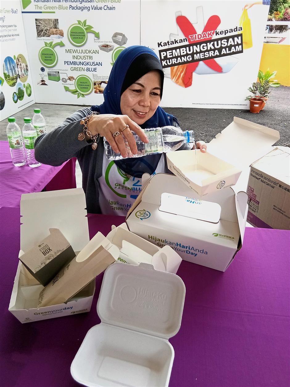 Noor Hayati testing a polyethylene-coated box to show that it can hold liquid.