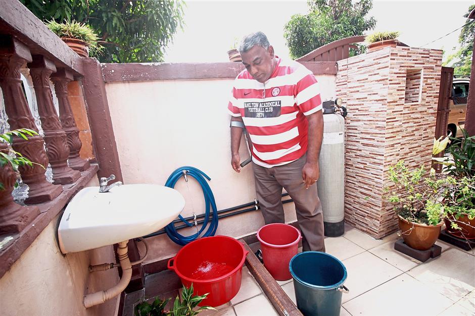 Mohamad Hussin Mydin from Taman Sentosa Klang storing water from the tap into container in view of the water.