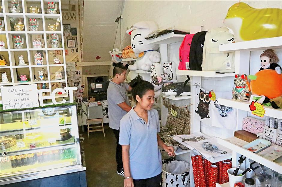 Purfect Cat Cafe manager Eugene Hoe (left) with his staff Atillia Zulkifli (foreground) at Purfect Cat Cafe in Muntri Street.