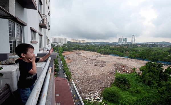 Unpleasant situation: A bulldozer (right) seen burying rubbish that is polluting the area around Taman Kinrara Mas.