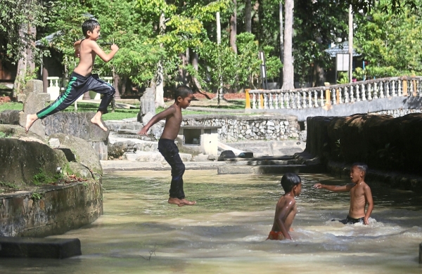 Children happily jumping into the river for a cool dip at the Bukit Panchor state park.