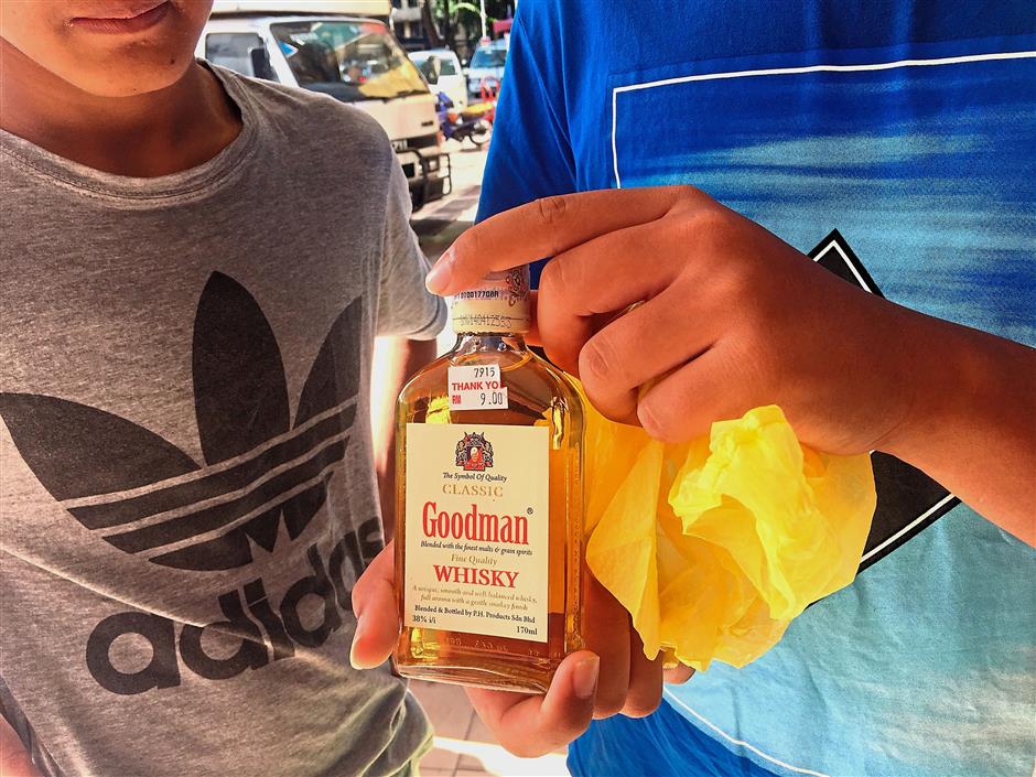 The two boys showing the bottle that they purchased earlier.